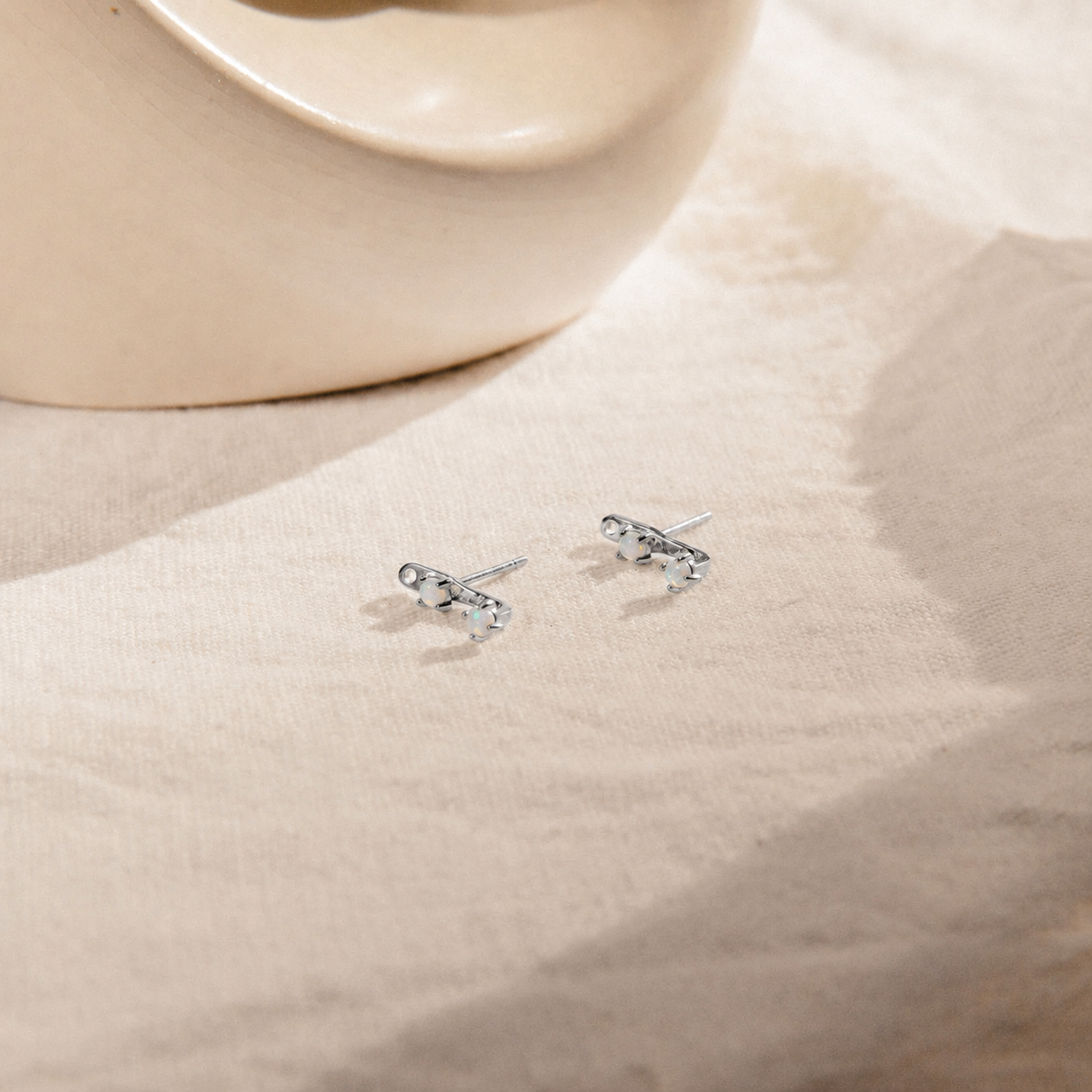 Pair of silver earrings on a beige fabric background